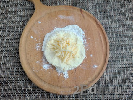 Скатать тесто на дощечке в шар, а затем сформировать лепёшку диаметром 3-4 см. По центру лепёшки выложить часть натёртого сыра.