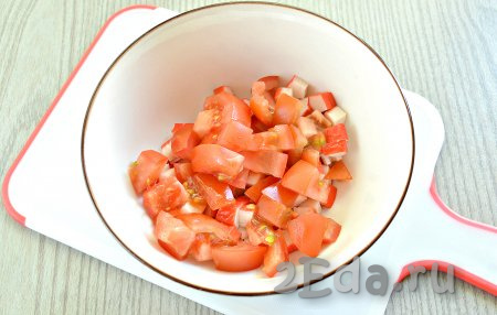 Промываем свежие помидоры, вырезаем плодоножку. Для этого салата лучше использовать упругие, спелые помидоры с минимальным содержанием мякоти. Нарезаем помидоры небольшими кусочками, добавляем в салатник с крабовыми палочками.