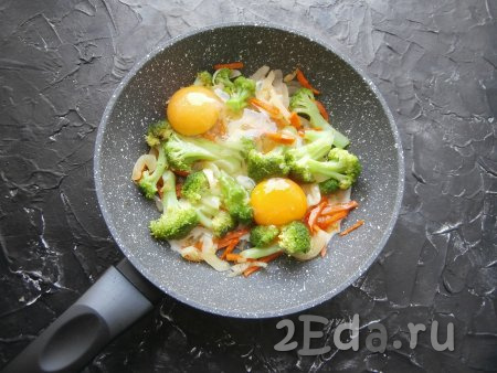 Посолить овощи по вкусу, перемешать и обжаривать в течение 3-4 минут, не забывая иногда перемешивать. Далее в сковороду с овощами разбить яйца, посолить их.