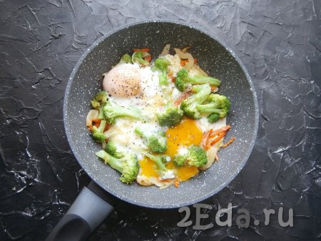 Готовить яичницу с брокколи под крышкой в течение 3-5 минут (до сворачивания белка). Блюдо поперчить.