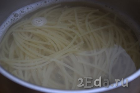 В кастрюлю с кипящей водой выложить спагетти, хорошо перемешать, посолить, а после закипания варить на небольшом огне в течение времени, указанного на упаковке (обычно спагетти варятся 7-9 минут).
