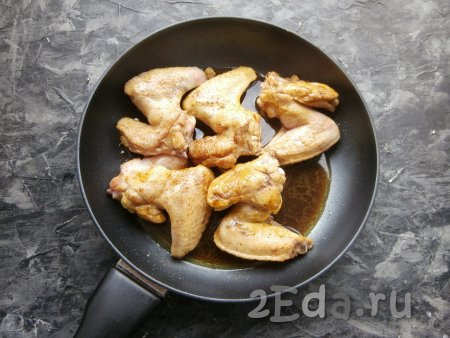 В сковороду с куриными крылышками влить соевый соус, смешанный с водой и лимонным соком.