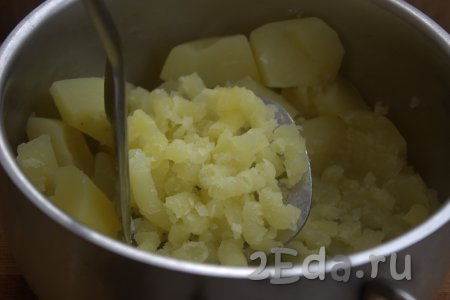 Затем слить из кастрюли всю воду и размять картофель с помощью толкушки в пюре.