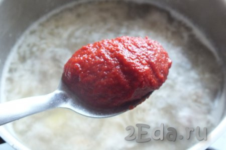 В кастрюлю с фаршем, обжаренным с картошкой, влейте 1,8-2 литра кипящей воды, добавьте очищенный и разрезанный на две половинки зубчик чеснока, проварите 15 минут. А затем извлеките чеснок, чтобы у супа не было горького привкуса. После того как уберёте чеснок, добавьте томатную пасту, перемешайте, доведите до кипения, убавьте огонь и варите 10 минут.