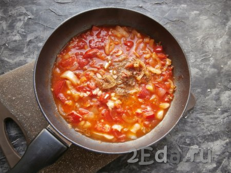 В сковороду влить горячую воду, добавить соль, специи для мяса, томатный соус, измельчённый чеснок, перемешать, дать получившемуся соусу закипеть, а затем потомить его на небольшом огне около 5 минут.