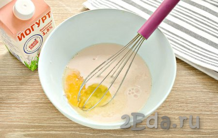 В миску вливаем питьевой йогурт, туда же вбиваем сырое куриное яйцо, всыпаем сахар и небольшую щепотку соли.