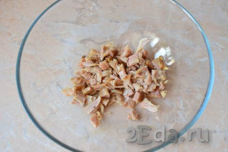Отделите мясо от костей, нарежьте на небольшие кусочки и выложите в объёмную миску, в которой будете готовить салат.
