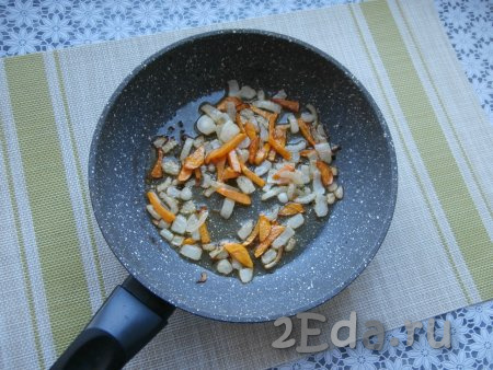Очищенную луковицу нарезать достаточно мелко, половину очищенной морковки нарезать соломкой (или брусочками), выложить на сковороду с растительным маслом и на среднем огне обжарить, иногда перемешивая, до мягкости овощей (на это потребуется 4-5 минут).