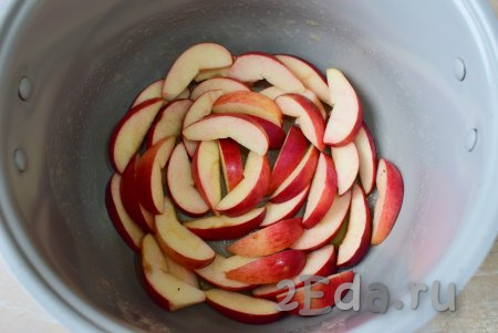 Яблоки помойте, удалите сердцевину и нарежьте ломтиками. Выложите половину нарезанных яблочных долек на дно чаши мультиварки.