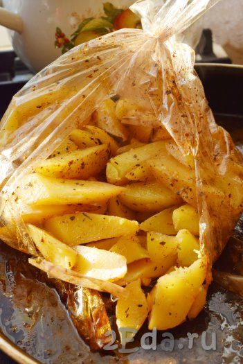 Готовый мягкий, вкусный и ароматный картофель достаём из духовки, разрезаем рукав и выкладываем картошку на блюдо для подачи.