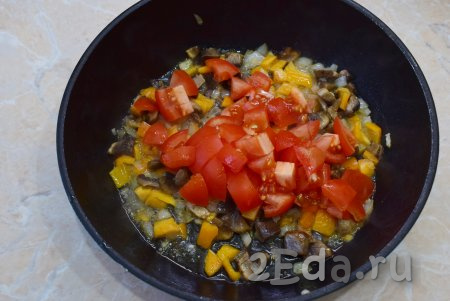 Следом добавьте нарезанные помидоры, перемешайте содержимое сковороды, накройте крышкой и оставьте тушиться на небольшом огне 4-5 минут. Болгарский перец должен стать достаточно мягким.