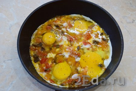 В сковороду к грибам и овощам вбейте сырые яйца. Посыпьте солью и специями. Готовьте ещё 3-5 минут (до готовности яиц). Большой огонь не делайте. Яйца должны полностью приготовиться, но не начать подгорать. Для ускорения процесса сковороду можно накрыть крышкой.