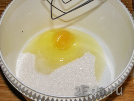 В достаточно объёмную миску (или в чашу для взбивания) насыпаем сахар, добавляем яйцо, с помощью венчика (или миксером) смешиваем практически до однородного состояния.