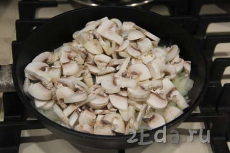 Шампиньоны промыть под водой и нарезать на пластинки. Выложить нарезанные грибы в сковороду к луку, хорошо перемешать.