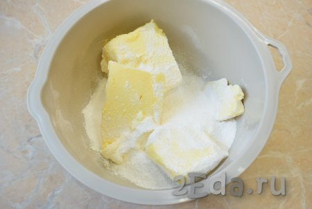 Сливочное масло заранее достаньте из холодильника, оставьте при комнатной температуре, чтобы оно стало мягким. Для того чтобы масло быстрее размягчилось, можно его нарезать на кусочки. В достаточно объёмную миску выложите мягкое сливочное масло, всыпьте сахар и смешайте их до однородности.