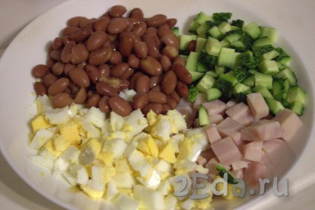 В глубокую тарелку выложить красную фасоль, нарезанные огурцы, яйца и ветчину.
