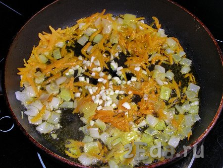 В сковородке прогреваем подсолнечное масло, выкладываем лук с морковкой и обжариваем в течение 3-5 минут (до прозрачности лука) на среднем огне, помешивая. Затем добавляем в сковороду нарезанный чеснок и обжариваем всё вместе ещё 2-3 минуты, периодически перемешивая.