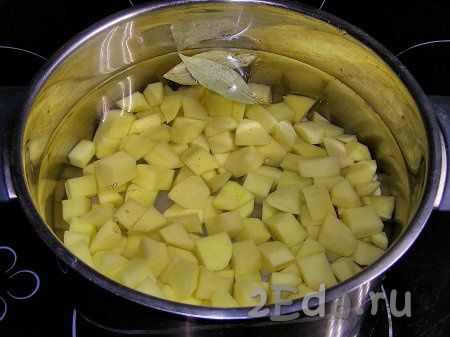 Перекладываем нарезанный картофель в кастрюлю, заливаем 1-1,5 литрами холодной водой, добавляем лавровые листья. Ставим кастрюлю на сильный огонь. Когда вода закипит, огонь уменьшаем почти до минимального и варим картофель ещё минут 10-15 (до мягкости).