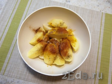 Картофельные дольки посыпать солью, куркумой, чёрным молотым перцем, паприкой и мускатным орехом, влить растительное масло.