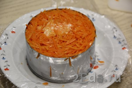 Если морковка по-корейски очень длинная, нарезать её на более короткие полоски и выложить поверх копчёной курицы, немного утрамбовать. Дать салату в течение 2-3 часов пропитаться, поместив тарелку с кольцом в холодильник.