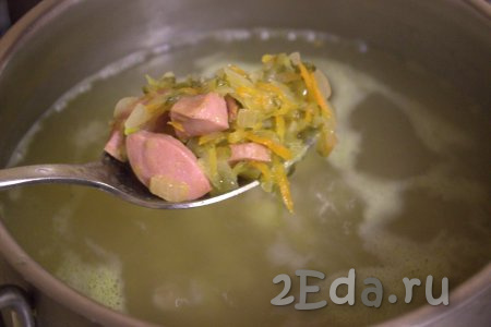 После того как картофель с перловкой станут мягкими (будут полностью готовы), переложить в кастрюлю обжаренные овощи с сосисками.