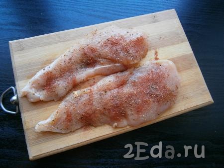 Разрезать куриное филе вдоль на 2 части потоньше. Посыпать мясо специями, солью, черным молотым перцем и паприкой.