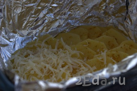 Картошку посыпать любимыми приправами (я использовала универсальную приправу для картофеля). Следующим слоем выложить 1/3 часть натёртого сыра и равномерно распределить по всему картофелю.