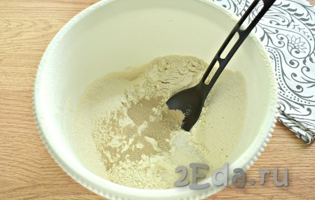 Вначале замесим дрожжевое тесто, для этого в объёмную миску просеиваем 2,5 стакана муки, добавляем сухие дрожжи, сахар и соль, хорошо перемешиваем, образуя в центре муки воронку.