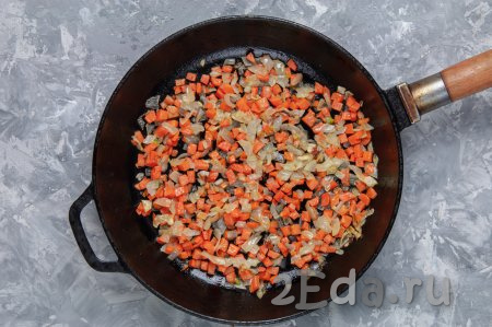 Сделайте зажарку, для этого на разогретую сковороду налейте 2 столовые ложки растительного масла, затем выложите лук с морковкой и на среднем огне обжарьте овощи в течение 7 минут (до мягкости моркови), иногда помешивая.