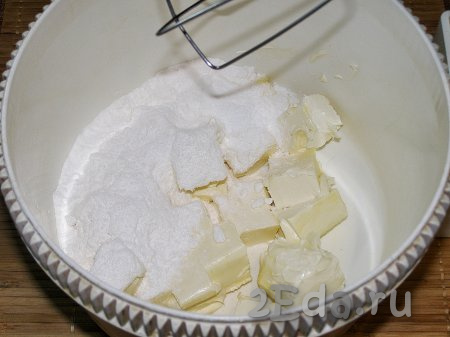Примерно за 1,5-2 часа до приготовления печенья нужно достать из холодильника сливочное масло и яйца, чтобы яйца прогрелись до комнатной температуры, а масло приобрело нужную мягкую консистенцию. Масло комнатной температуры нарезаем на кубики, выкладываем в ёмкость, удобную для взбивания, добавляем сахарную пудру и перемешиваем миксером до однородной, пышной массы. Обратите внимание на то, что сливочное масло нужно именно согреть, его нельзя растапливать на плите или в микроволновке, так как тесто получится жидким и не будет держать форму.