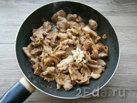Жарить свиную грудинку на небольшом огне около 15 минут, периодически мясо перемешивая (до румяного цвета). Затем добавить измельченный чеснок.