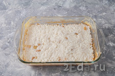 Выложите рис, смешанный с изюмом, в форму для запекания, разровняйте поверхность ложкой.