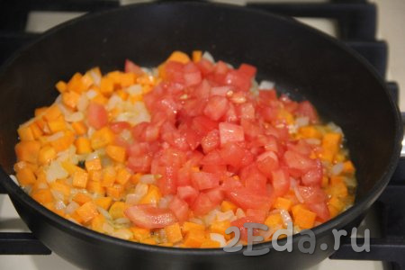 Помидор достать из воды, снять шкурку и нарезать его достаточно мелко. Добавить помидор в сковороду к овощам, перемешать и обжаривать, иногда помешивая, 3-5 минут.