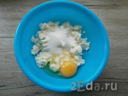 В творог добавить яйцо, щепотку соли, всыпать сахар.