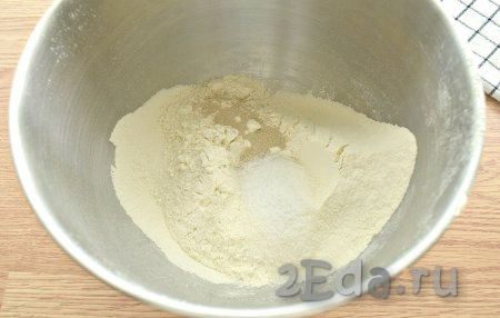 Прежде всего замесим тесто, для этого просеиваем в объёмную миску муку, добавляем к ней сахар, соль и сухие дрожжи, сразу перемешиваем.
