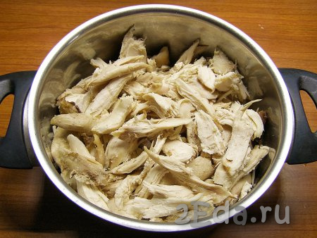 С остывшей курицы снимаем кожицу, а затем отделяем куриное мясо от костей, перекладываем в миску. Крупные куски мяса можно нарезать помельче.