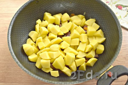 Очищенную картошку нарезаем на средние кубики, добавляем на сковороду с овощами и копчёными рёбрышками.