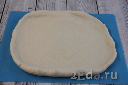 Переложить поднявшееся тесто на силиконовый коврик (или на стол, присыпанный мукой) и обмять. Раскатать тесто в не тонкий прямоугольный пласт.