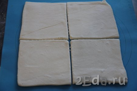 Пласт слоёного теста слегка раскатать на силиконовом коврике (или на припылённой мукой поверхности) и разрезать на 4 квадрата.