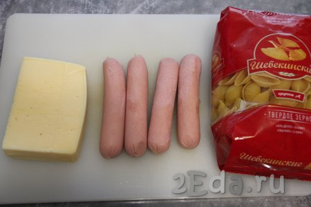 Подготовить продукты для приготовления макарон с сосисками и сыром на сковороде. Сосиски очистить от плёнки.