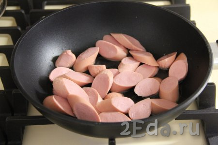 В сковороду влить немного масла и выложить сосиски, нарезанные на средние кружочки (тонко нарезать не нужно).