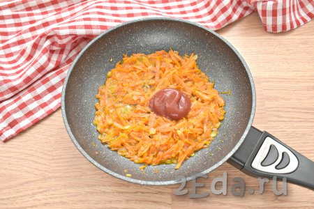 К луку и морковке добавляем томатную пасту, вливаем 2-3 столовых ложки бульона из кастрюли, перемешиваем и тушим овощи 3-4 минуты.