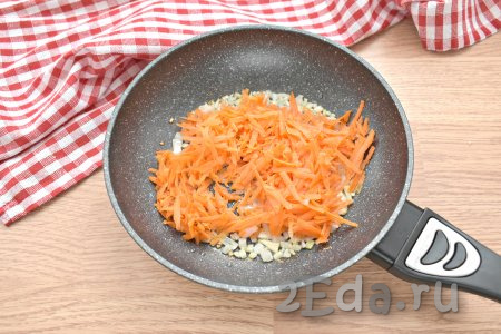 Очищенную морковку, натёртую на крупной тёрке, выкладываем к обжаренному луку. Обжариваем овощи минут 5, не забывая перемешивать.