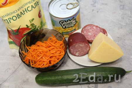 Подготовить продукты для приготовления салата с копчёной колбасой, свежим огурцом и корейской морковью. Корейскую морковку можно приобрести в магазине или на рынке, а можно приготовить и в домашних условиях.