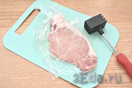 Получившиеся стейки из свинины накрываем пищевой плёнкой и отбиваем молоточком для мяса.