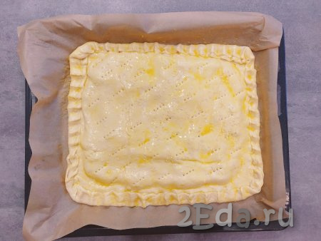 Поверхность слоёного пирога смазываем яичным желтком и посыпаем сверху кунжутом.