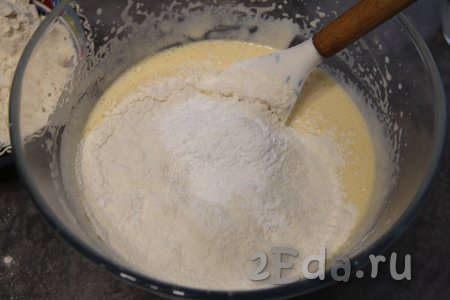 Затем в смесь яиц, кефира и масла добавить разрыхлитель, частями начать всыпать просеянную муку, перемешивая тесто лопаткой.