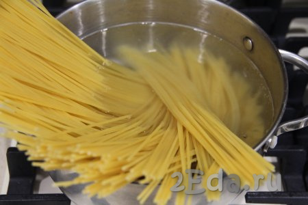 В кастрюлю, в которой будете варить спагетти, влить воду, поставить на сильный огонь. После закипания воду подсолить, опустить в неё спагетти, перемешать и после повторного закипания убавить огонь. Варить спагетти до готовности в течение времени, указанного в инструкции к макаронным изделиям, которые вы готовите (обычно на варку требуется 7-9 минут). 