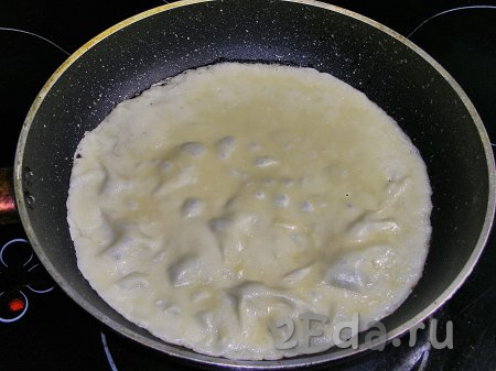 Сковородку для этих блинов нужно взять диаметром 20-22 сантиметра. Наливаем в сковороду немного растительного масла и сильно нагреваем. В горячую сковородку вливаем половник теста, наклоняем сковороду, чтобы тесто равномерно распределилось по дну. Жарим блинчик на среднем огне примерно 1-2 минуты. Готовый блин подрумянится и будет легко отставать от сковороды.
