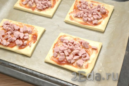 Колбасу нарезаем на маленькие кубики, размещаем ровным слоем на тесто. Раскладывая начинку для мини-пицц (колбасу, овощи и сыр), учитывайте, что из двух слоёв теста мы будем формировать 8 мини-пицц и начинку соответственно нужно делить на 8 равных частей.